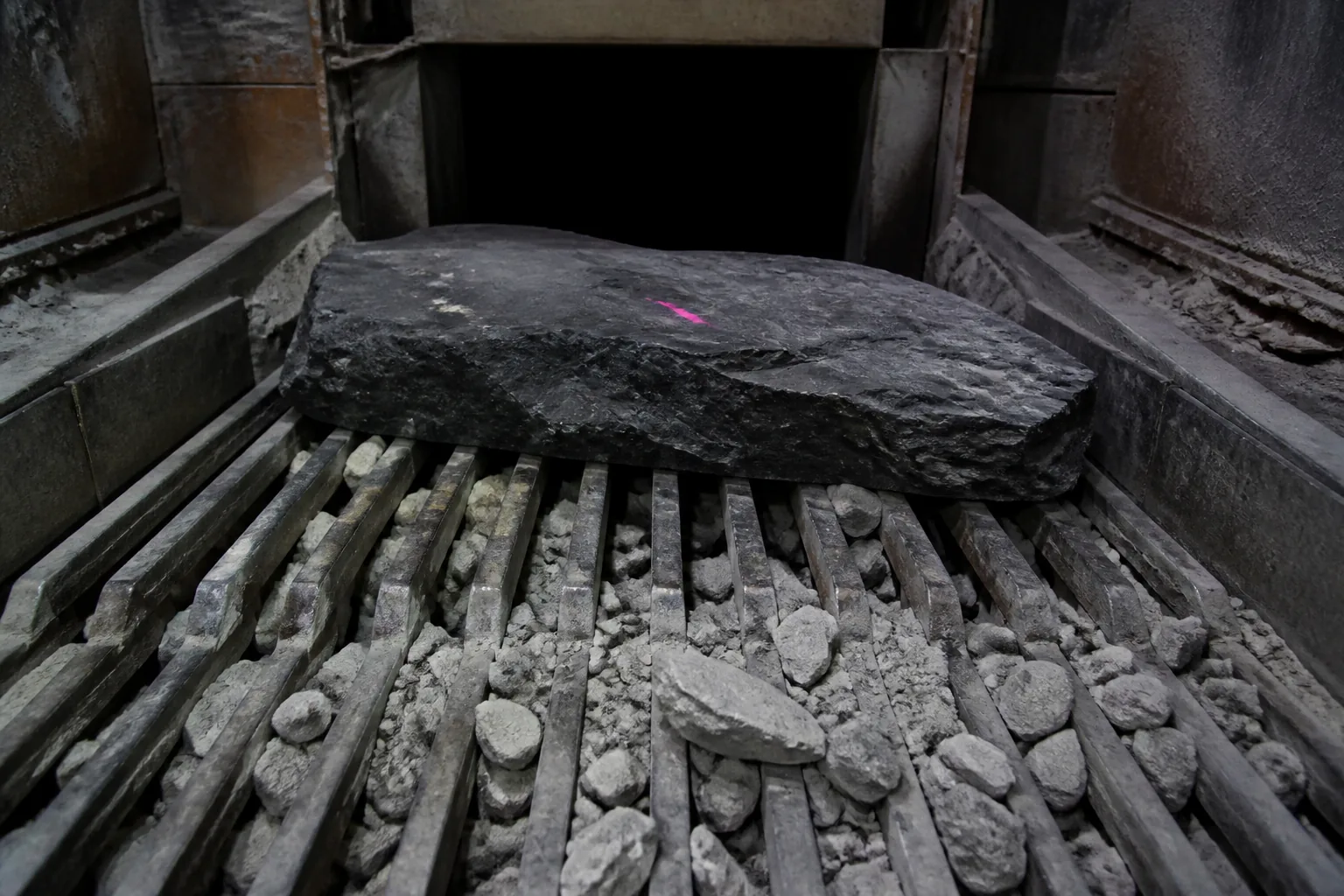 Oversize slab held at grizzly above an unlit transfer chute